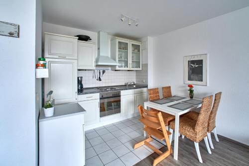 a kitchen with white cabinets and a table and chairs at Ferienwohnung Bootsteg Moba-Travel in Priwall