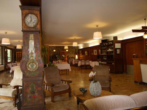um grande relógio avô numa sala de estar com cadeiras em Hôtel Le Castelet em Ax-les-Thermes