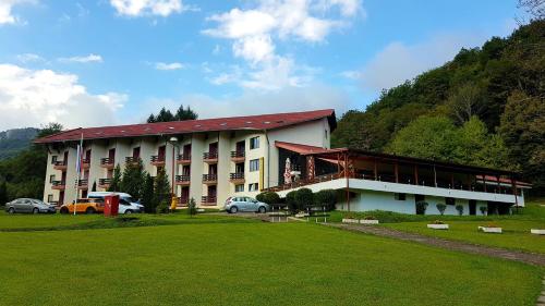 a large building with cars parked in front of it at Hotel Mladost in Tjentište