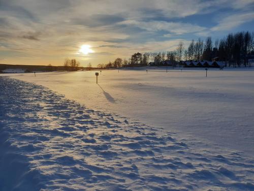 a snow covered field with the sun setting in the distance at First Camp Frösön-Östersund in Frösö