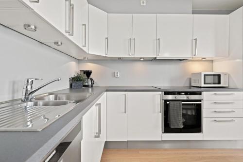 a white kitchen with a sink and a microwave at BJØRVIKA APARTMENTS, Solsiden Area, Trondheim city center in Trondheim