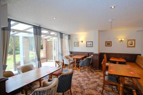 a restaurant with wooden tables and chairs and windows at SPITTAL BROOK in Stafford