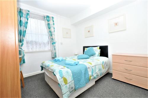 a bedroom with a bed and a dresser and a window at The Waterfront in Greenock