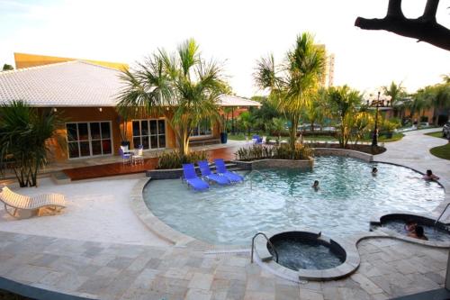 a large swimming pool with blue chairs and palm trees at Apartamento no Olimpia Park Resort in Olímpia