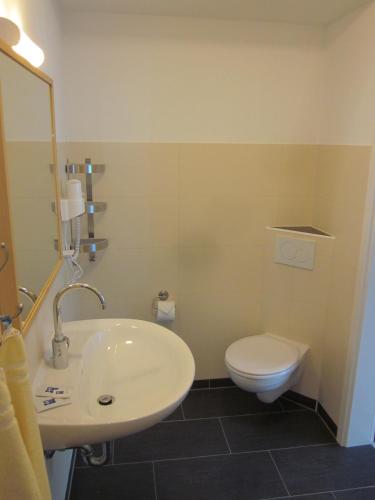 a bathroom with a white sink and a toilet at Hotel Waldesruh in Düsseldorf