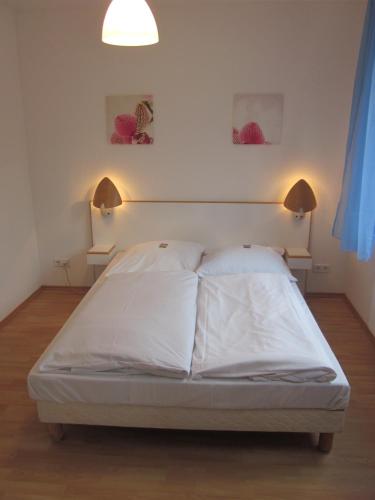 a bed in a room with two lights on the wall at Hotel Waldesruh in Düsseldorf