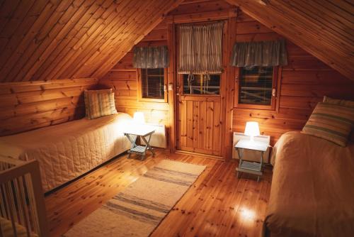 a bedroom with two beds in a log cabin at Lovely Cottage by Ounasjoki in Marraskoski