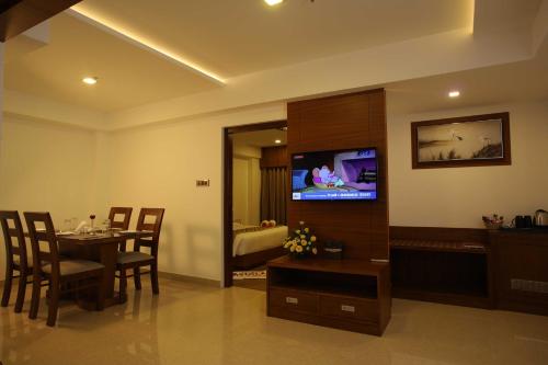 a dining room with a table and a flat screen tv at Hotel Karthika Park in Kazhakuttam