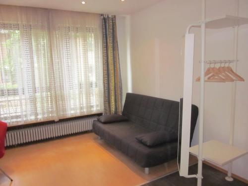 a living room with a couch in front of a window at Hotel Waldesruh in Düsseldorf