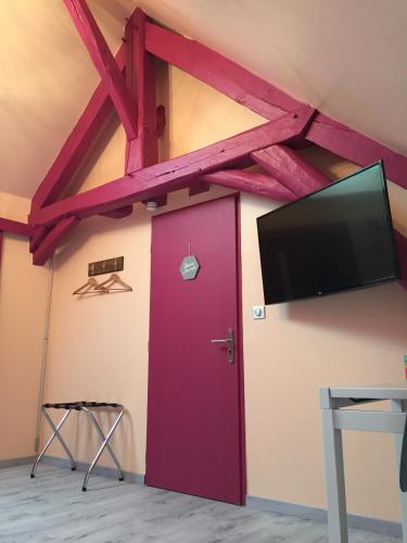 a room with a purple door and a flat screen tv at Le Rouge & Blanc in Mormont