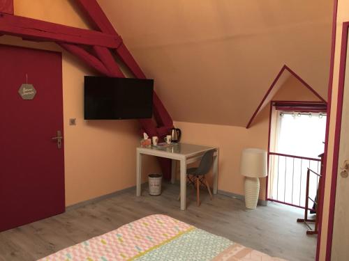 a bedroom with a desk and a tv on the wall at Le Rouge & Blanc in Mormont