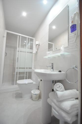 a white bathroom with a sink and a toilet at Hotel Goya in Almuñécar