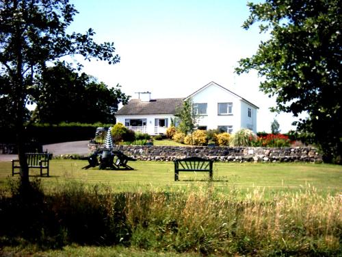 two park benches in a field in front of a house at The Waterfront House Country Home in Oughterard
