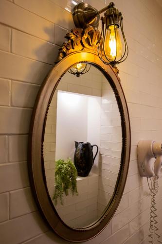 a mirror on a wall with a lamp and a vase at NINHO SALOIO in Venda do Pinheiro