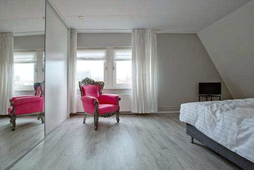 a bedroom with two chairs and a bed and a mirror at At Sea in Katwijk aan Zee
