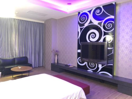a hotel room with a bed and a tv on a wall at Idee SPA Motel in Yangmei