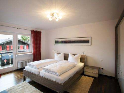 een slaapkamer met een bed met witte lakens en een raam bij Bergspitze in Garmisch-Partenkirchen