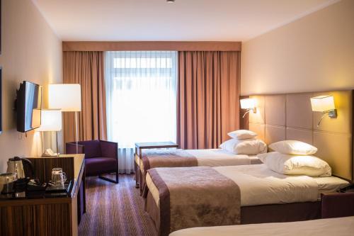 a hotel room with two beds and a window at Hotel DeSilva Premium Opole in Opole