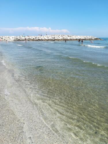 a beach with a group of people in the water at La Brigata Apartments Orange House in Cavallino-Treporti