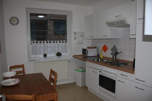 a kitchen with white cabinets and a table and a window at Andrea in Lübeck