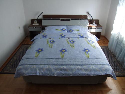 una camera da letto con un letto con un piumone blu e fiori sopra di Đokić apartmani a Soko Banja