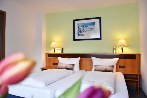 a bedroom with two beds and two lamps and flowers at Landhotel Zum Hirsch in Unterweißbach