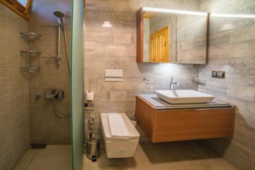 a bathroom with a sink and a toilet and a mirror at Nerissa Hotel in Cıralı