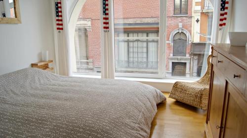 a bedroom with a bed and a large window at Little Suite - Théo in Lille