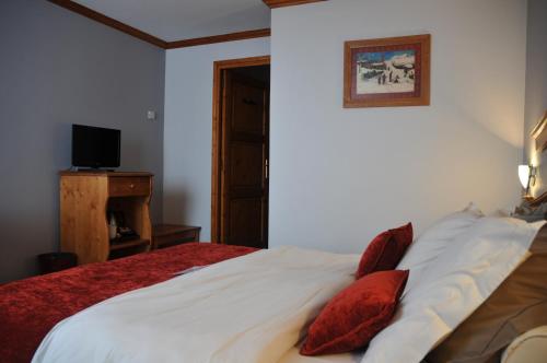 a bedroom with a bed with red pillows and a television at Le Calgary in Les Saisies