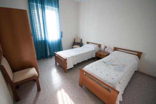 a bedroom with two beds and a chair and a window at Villetta nel Verde in Ascea