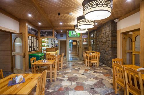 a restaurant with wooden tables and chairs and a stone wall at Schronisko PTTK Trzy Korony in Sromowce Niżne
