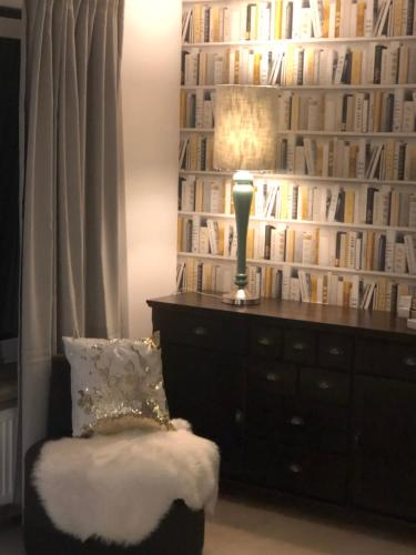 a room with a book wall with a lamp and a chair at Hotel Imperium in Chełmża