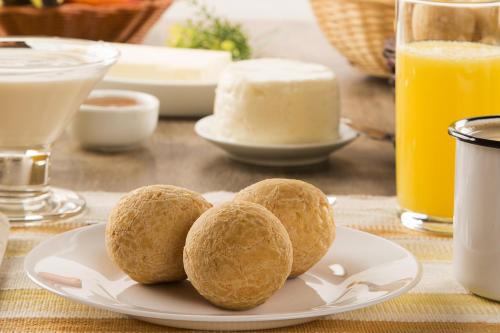 un piatto con tre rotoli su un tavolo con succo d'arancia di Pousada Café da Roça a Campos Gerais