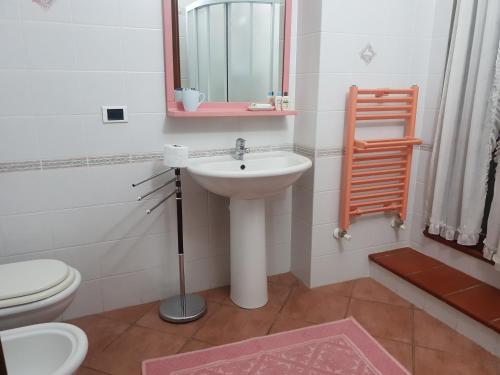 a bathroom with a sink and a toilet and a mirror at Villetta Porto Corallo in Villaputzu