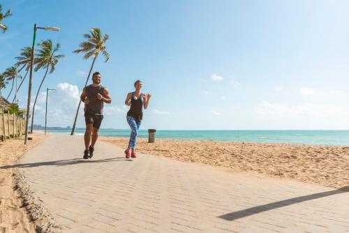two people running on the beach at Hotel Brisa Praia Pajuçara in Maceió