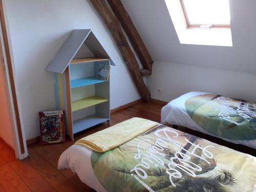 a attic bedroom with two beds and a book shelf at la maison de maelys in Courcelles-lès-Gisors