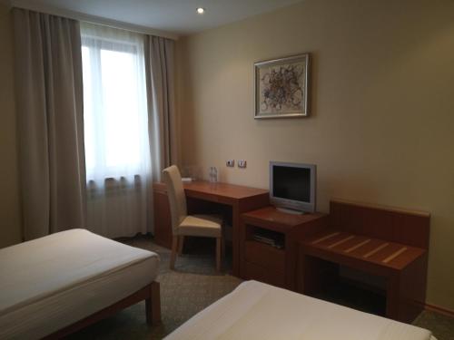 a hotel room with a desk with a computer and a bed at Hotel Park Central in Sliven