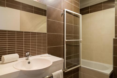 a bathroom with a sink and a shower at The Originals City, Hôtel Dau Ly, Lyon Est (Inter-Hotel) in Bron