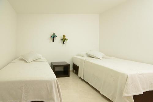 2 Betten in einem weißen Zimmer mit Kreuzen an der Wand in der Unterkunft Acogedor Apartamento 2 Habitaciones S31 in Envigado