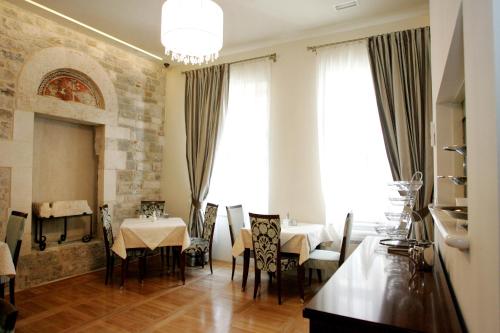 a dining room with a table and chairs and windows at Palace Augubio in Split
