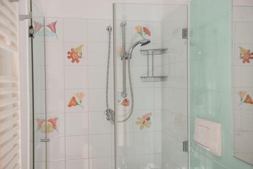 a shower with a glass door with flowers on the wall at Central Apartment - Residenza Battistessa in Caserta