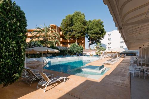 a swimming pool with chairs and umbrellas next to a building at Bellevue Vistanova in Magaluf