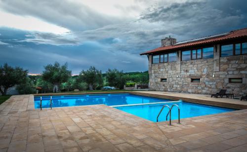 a swimming pool in front of a stone house at Quinta do Olival in Vilas Boas