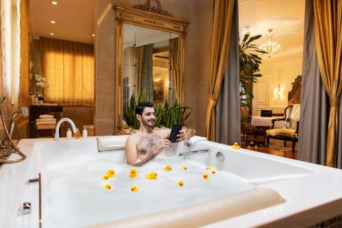 a man in a bath tub holding a cell phone at Radisson Blu GHR Rome in Rome