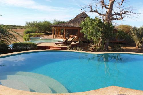 une grande piscine bleue avec un kiosque dans l'établissement Le Lodge Dalaal Diam, à La Somone