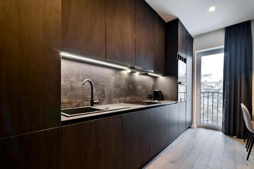 a kitchen with wooden cabinets and a sink and a window at City Center loft 2 in Kaunas