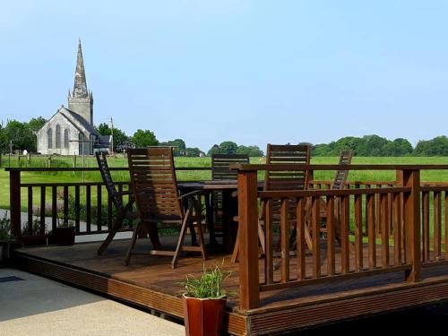 a deck with chairs and a table and a church at Lake Avenue House in Ballyconnell