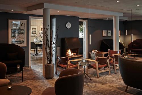a lobby with a fireplace and chairs and a table at Comwell Kongebrogaarden in Middelfart