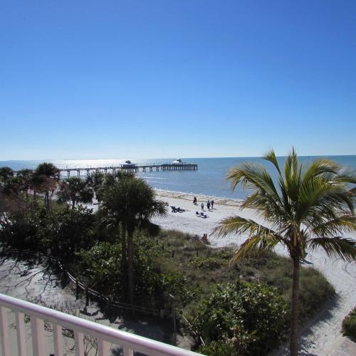 a beach with palm trees and a pier at Edison Beach House in Fort Myers Beach
