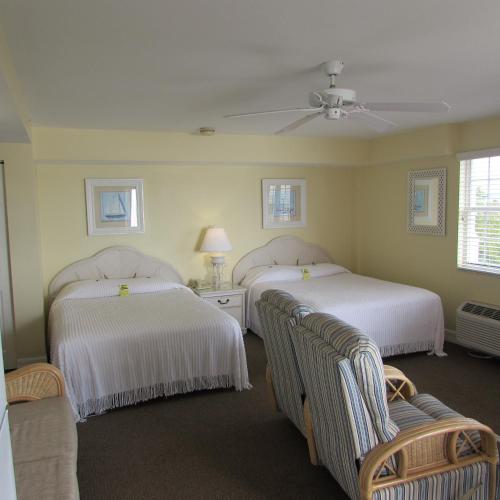 two beds in a room with two chairs at Edison Beach House in Fort Myers Beach